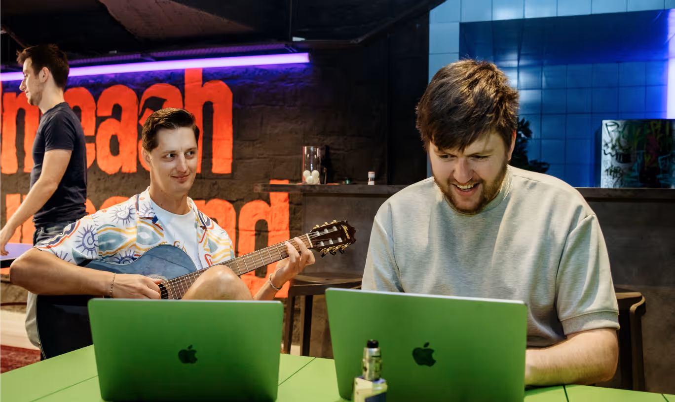 Muse Group team members playing guitar and working on laptops in a creative office