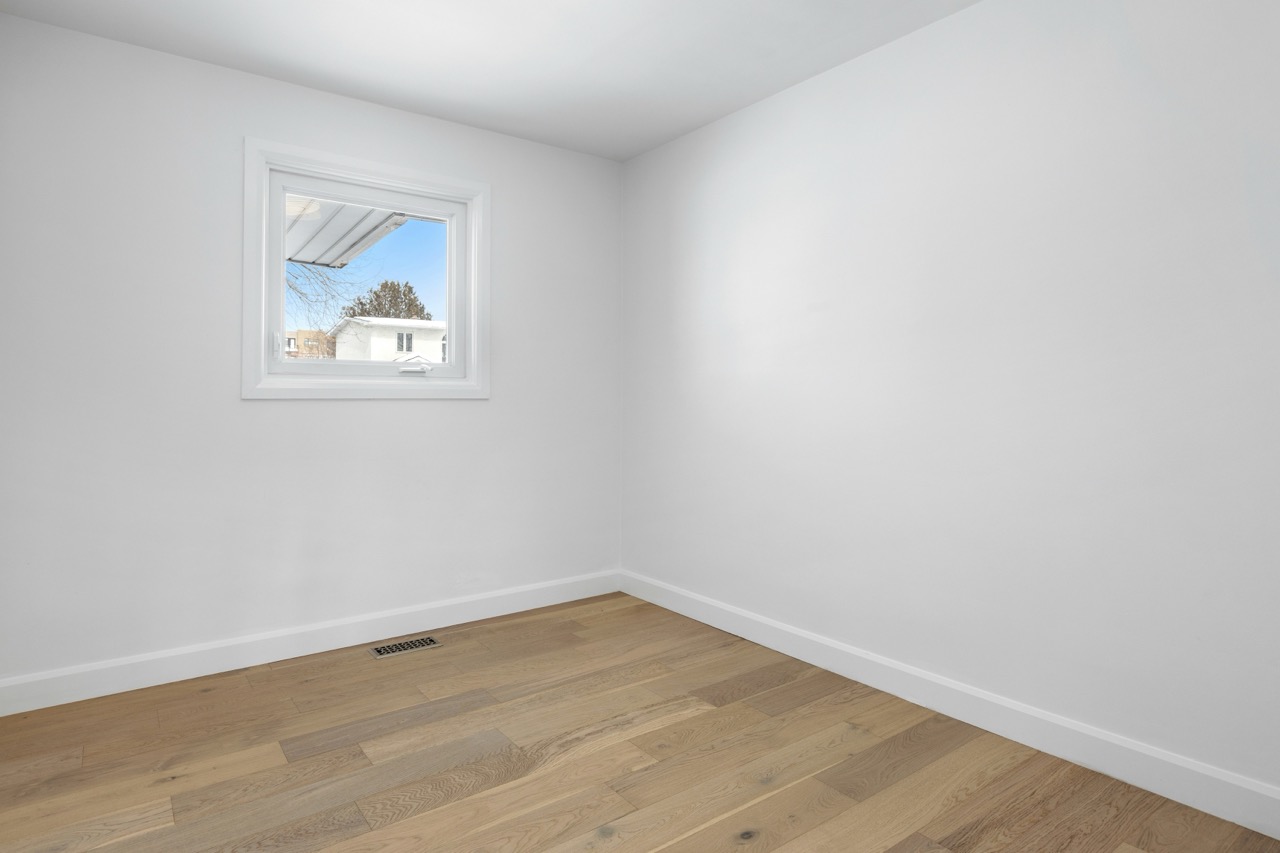 Newly renovated room with hardwood floors and a window