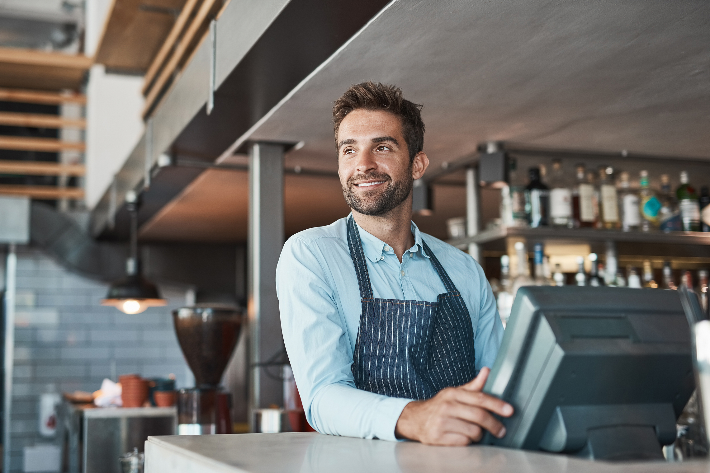 Male small business owner managing his café operations on a Point of Sale device.