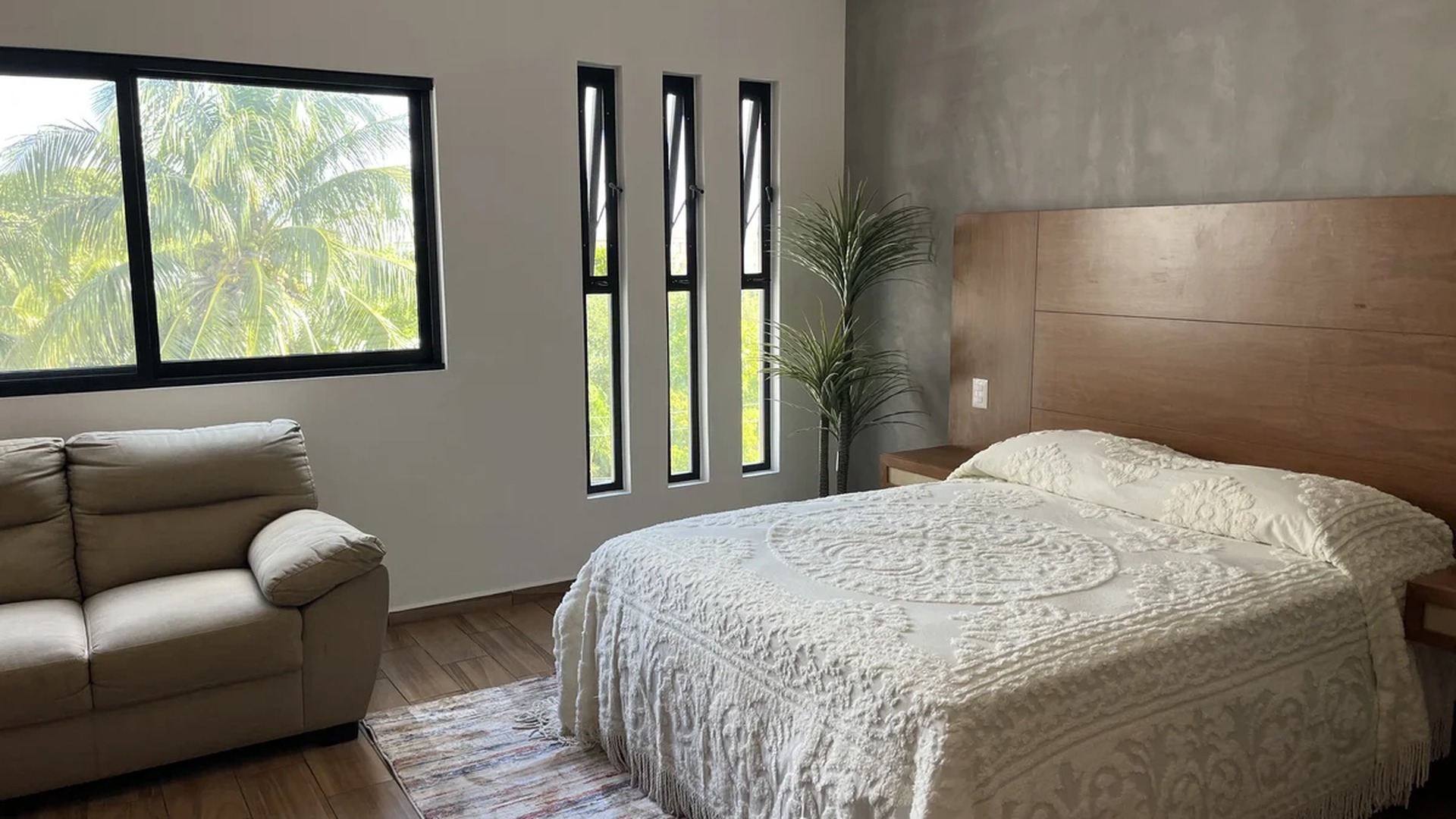 Image of a Spacious Bedroom, featuring Concrete Accent Wall and Wood-look Tile Flooring.