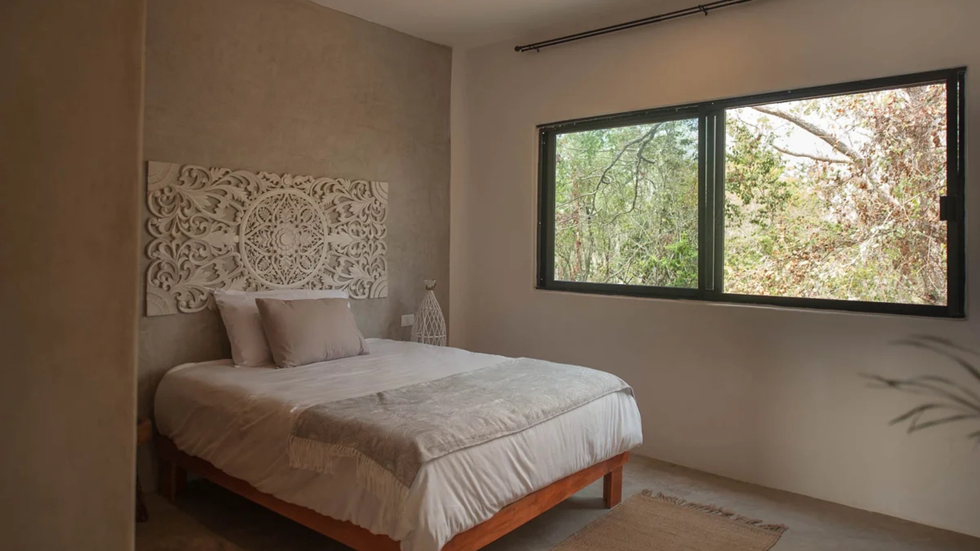 Image of a Bedroom, featuring Polished Concrete Walls and Carved Wooden Headboard.