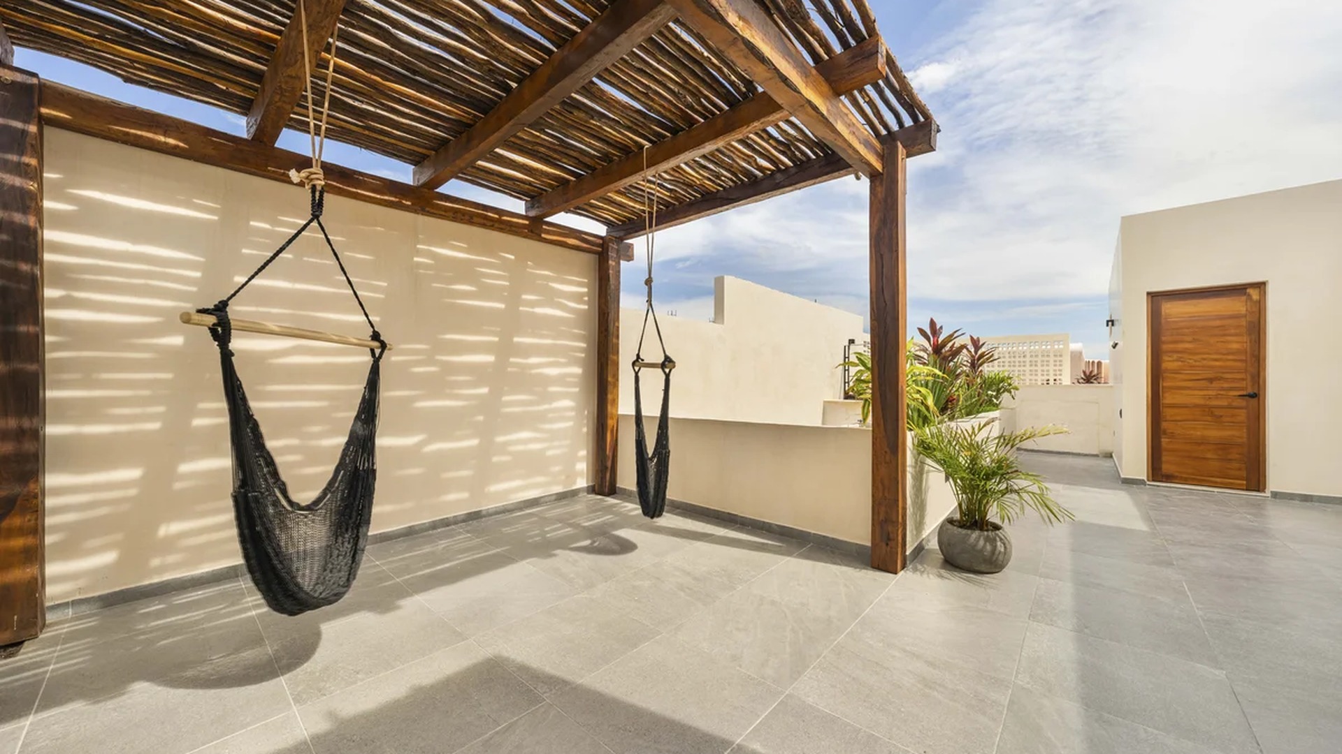 Image of a Rooftop Terrace, featuring Wooden Pergola and Hanging Hammock Chairs.