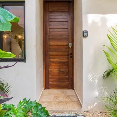 Image of a Tropical Entryway, featuring Hardwood Front Door and Lush Landscaping.