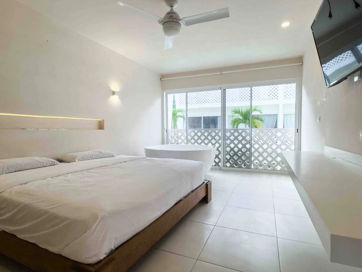 View of Modern Bedroom at Menotto 11, showcasing Minimalist Design, Freestanding Bathtub.