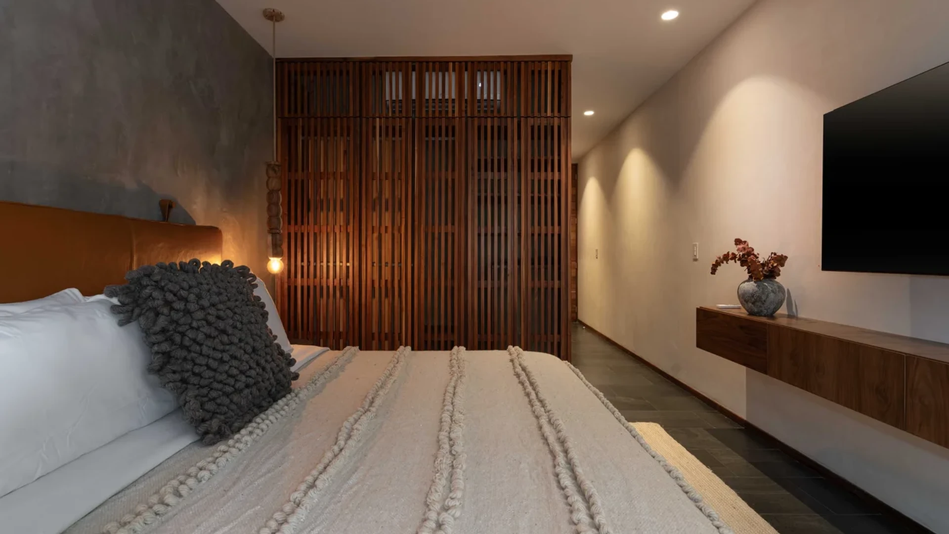 View of Modern Bedroom at Miraluna, showcasing Wood Accent Wall, Concrete Finish Wall.