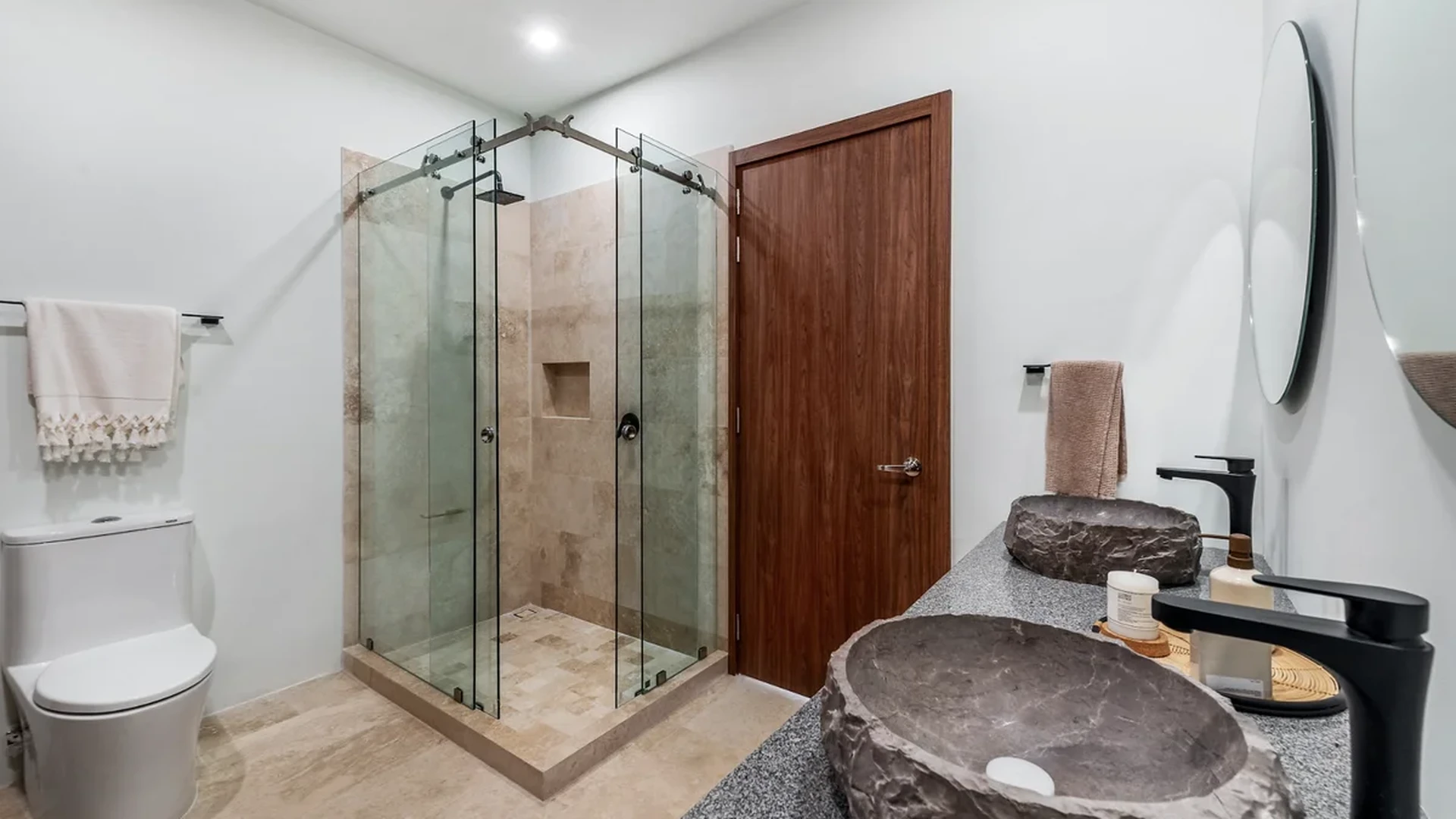 View of Modern Bathroom at BeUTiful, showcasing Stone Vessel Sinks, Glass Shower Enclosure.