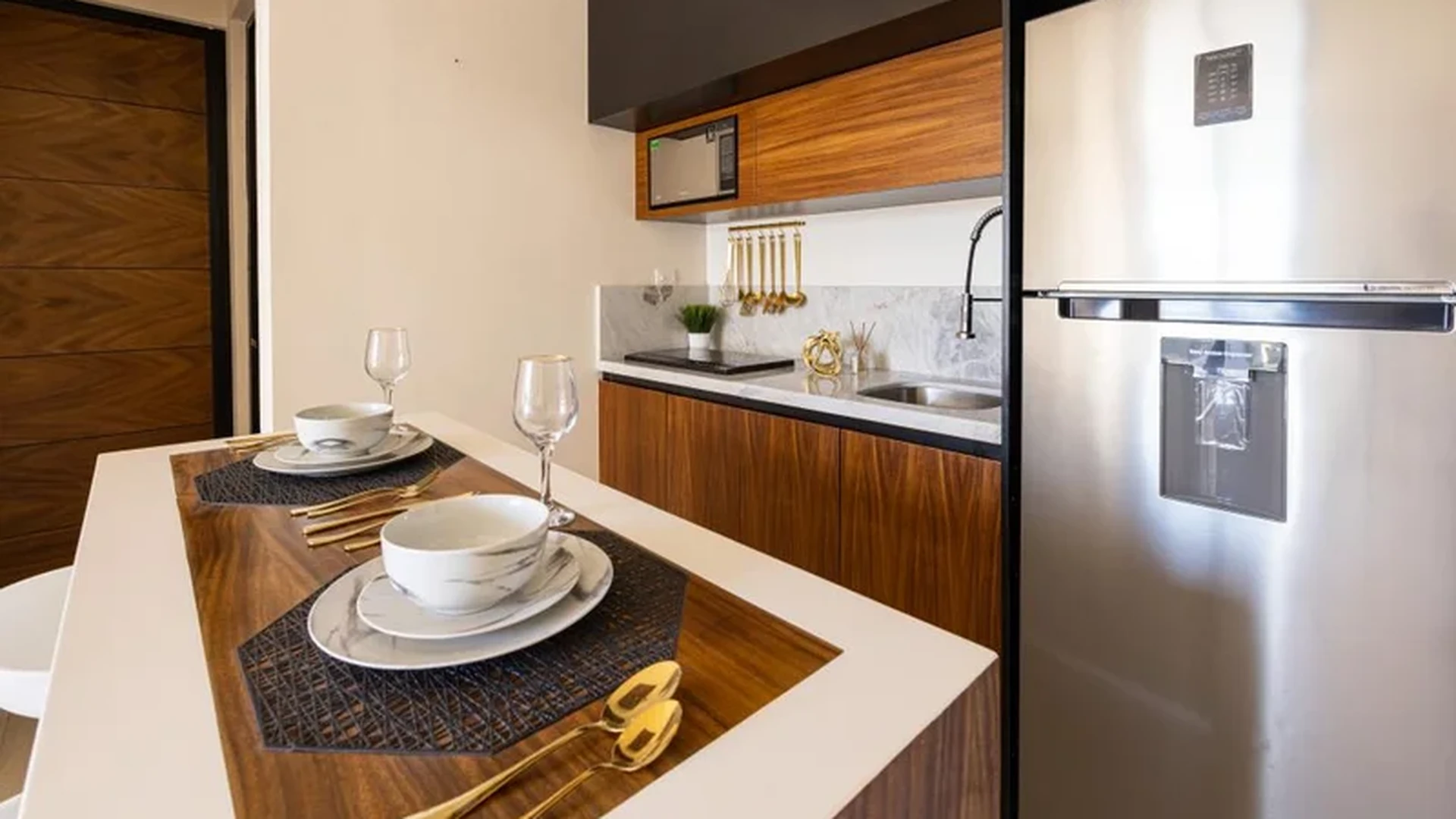 View of Modern Kitchenette at Mya Black Diamond, showcasing Stainless Steel Appliances, Wood Cabinetry.