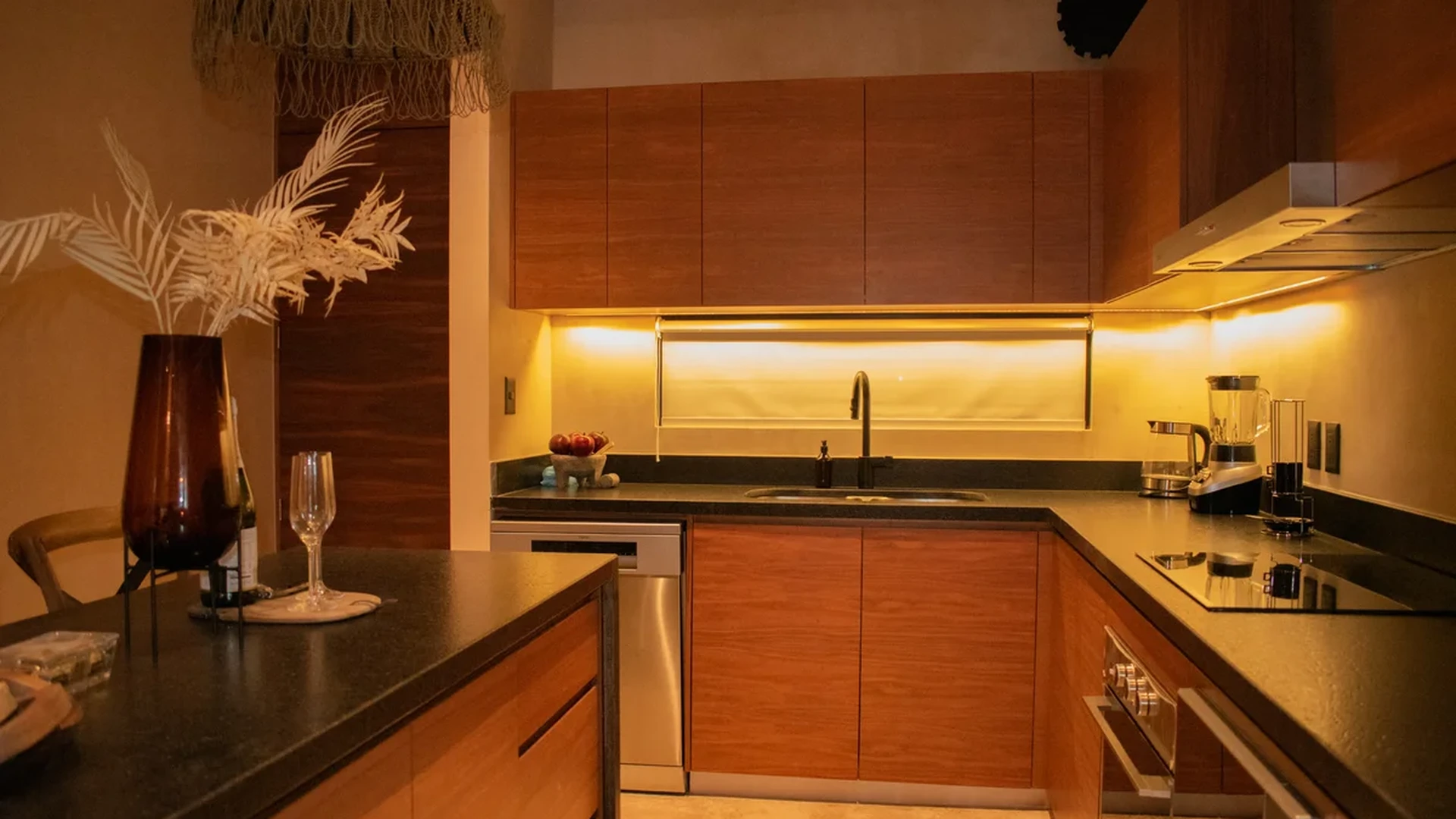 View of Modern Kitchen at Deja Vu, showcasing Wood Cabinetry, Black Countertops.