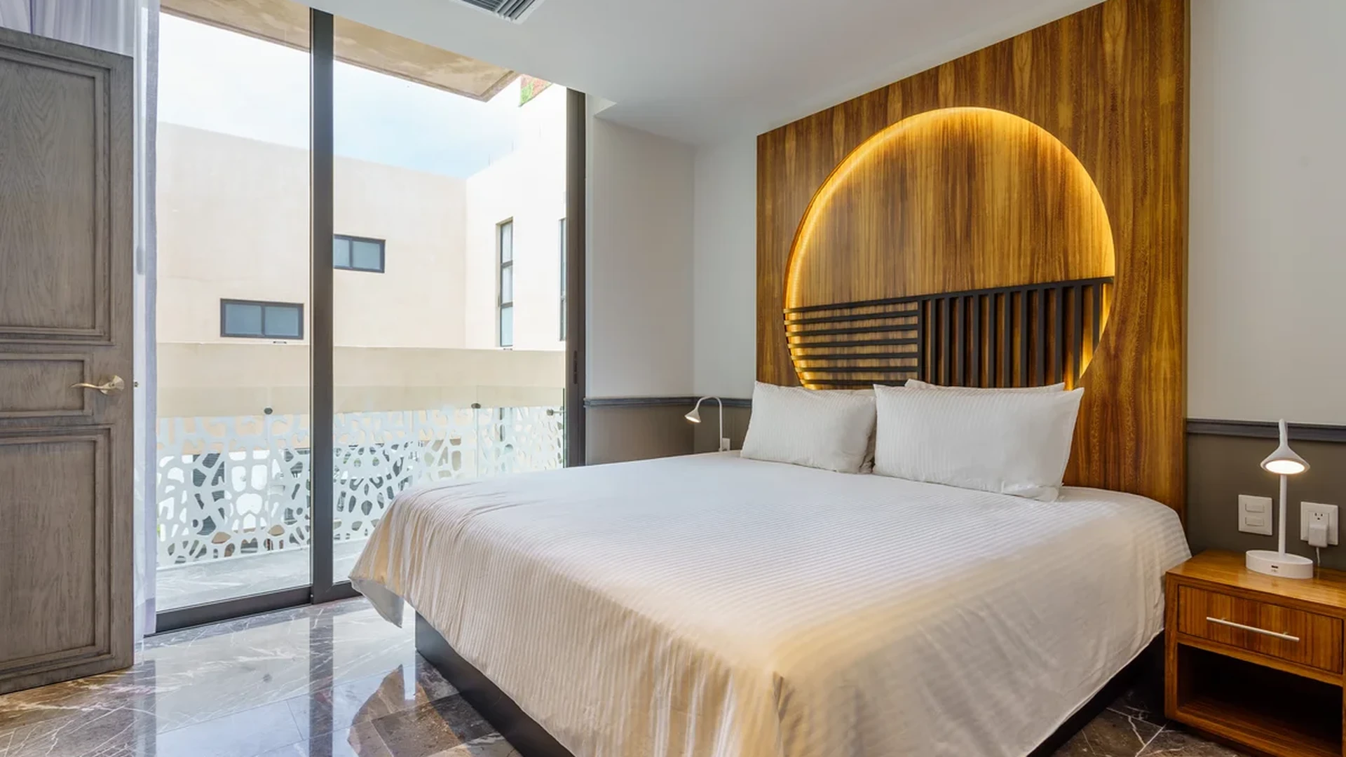 View of Modern Bedroom at Singular Joy, showcasing Marble Flooring, Wood Accent Wall.