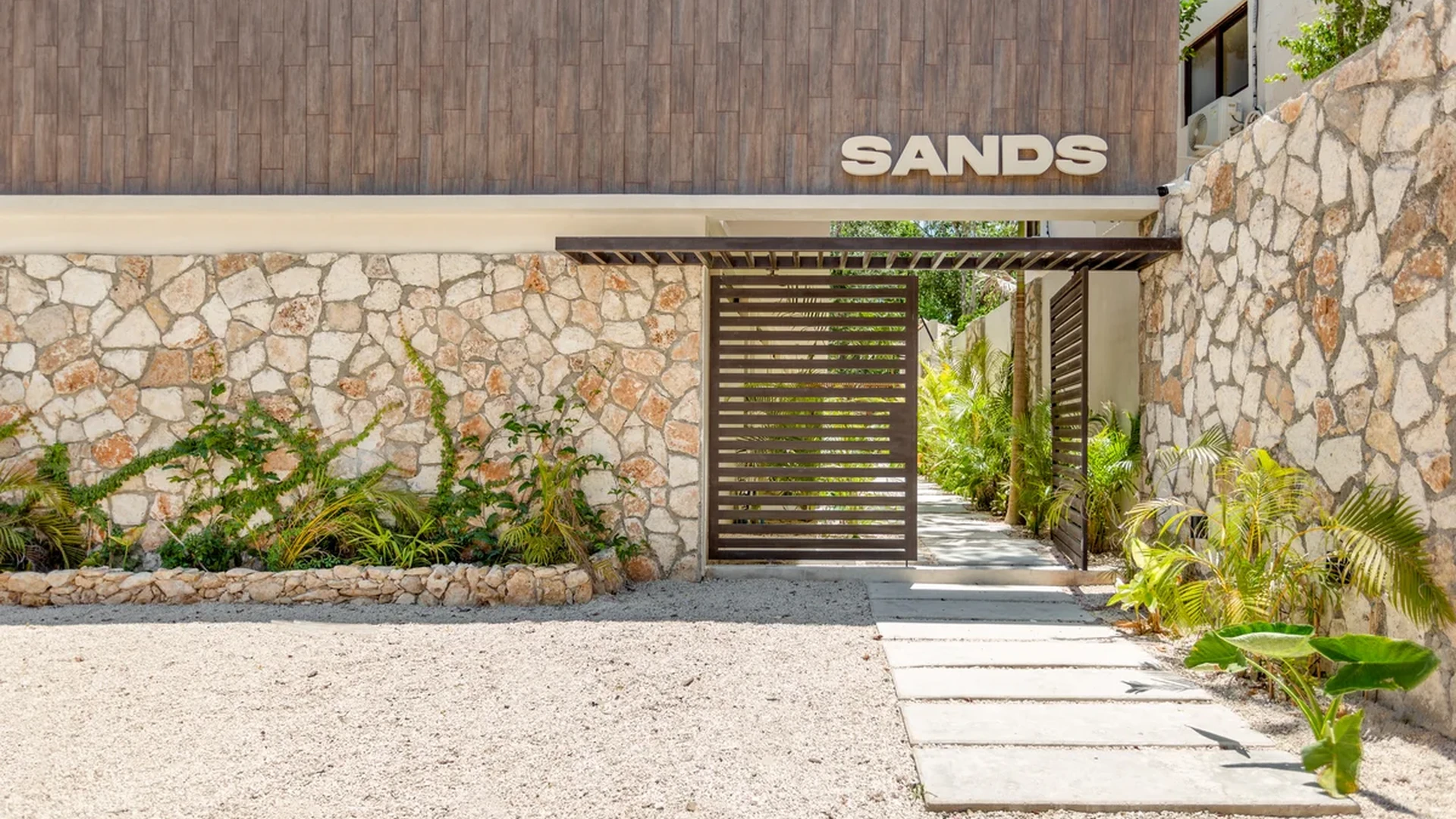 View of Building Entrance at Sands Tulum, showcasing Stone Facade, Modern Exterior.