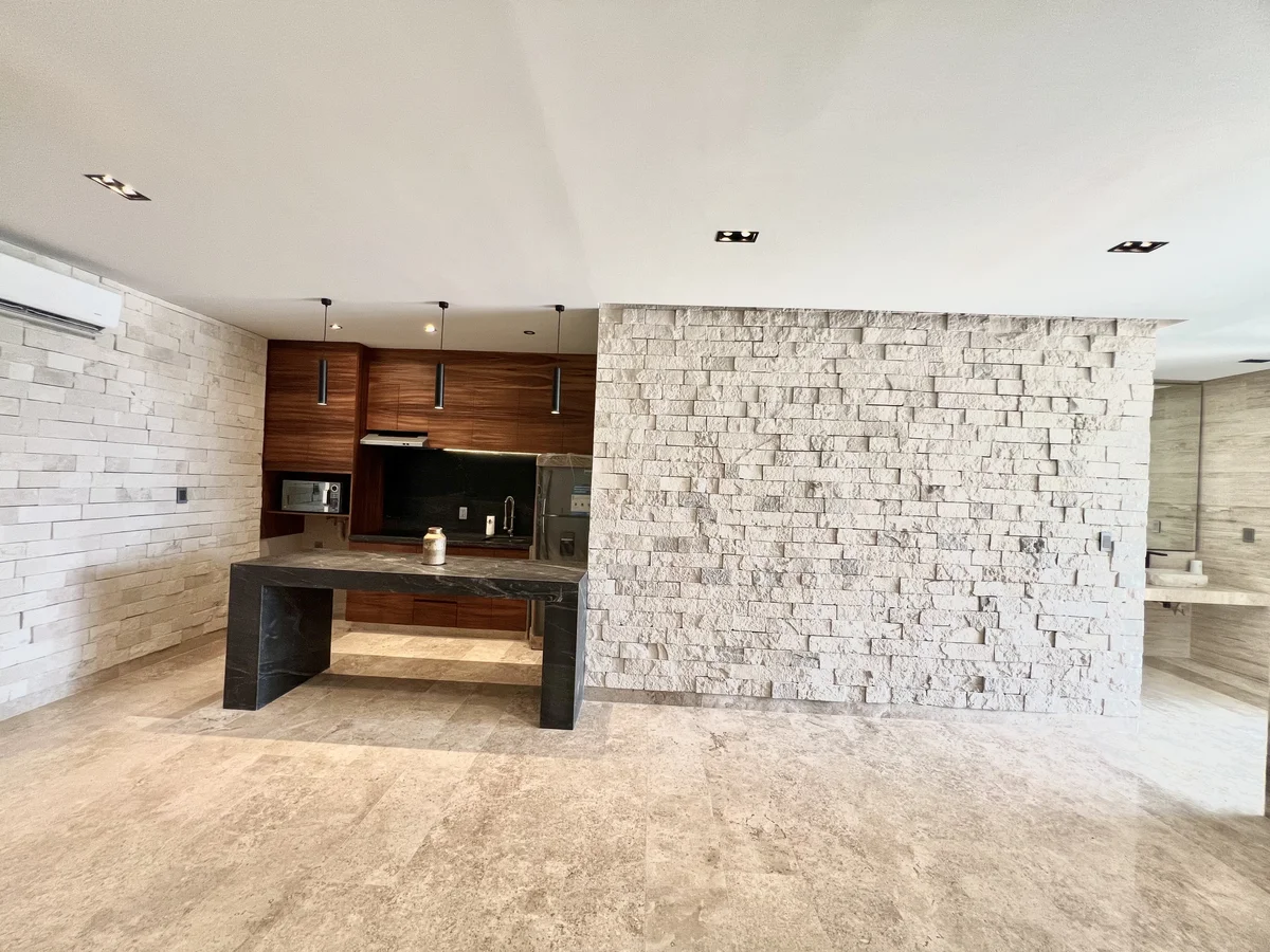 View of Modern Kitchen at Amaru, showcasing Stone Accent Wall, Kitchen Island.