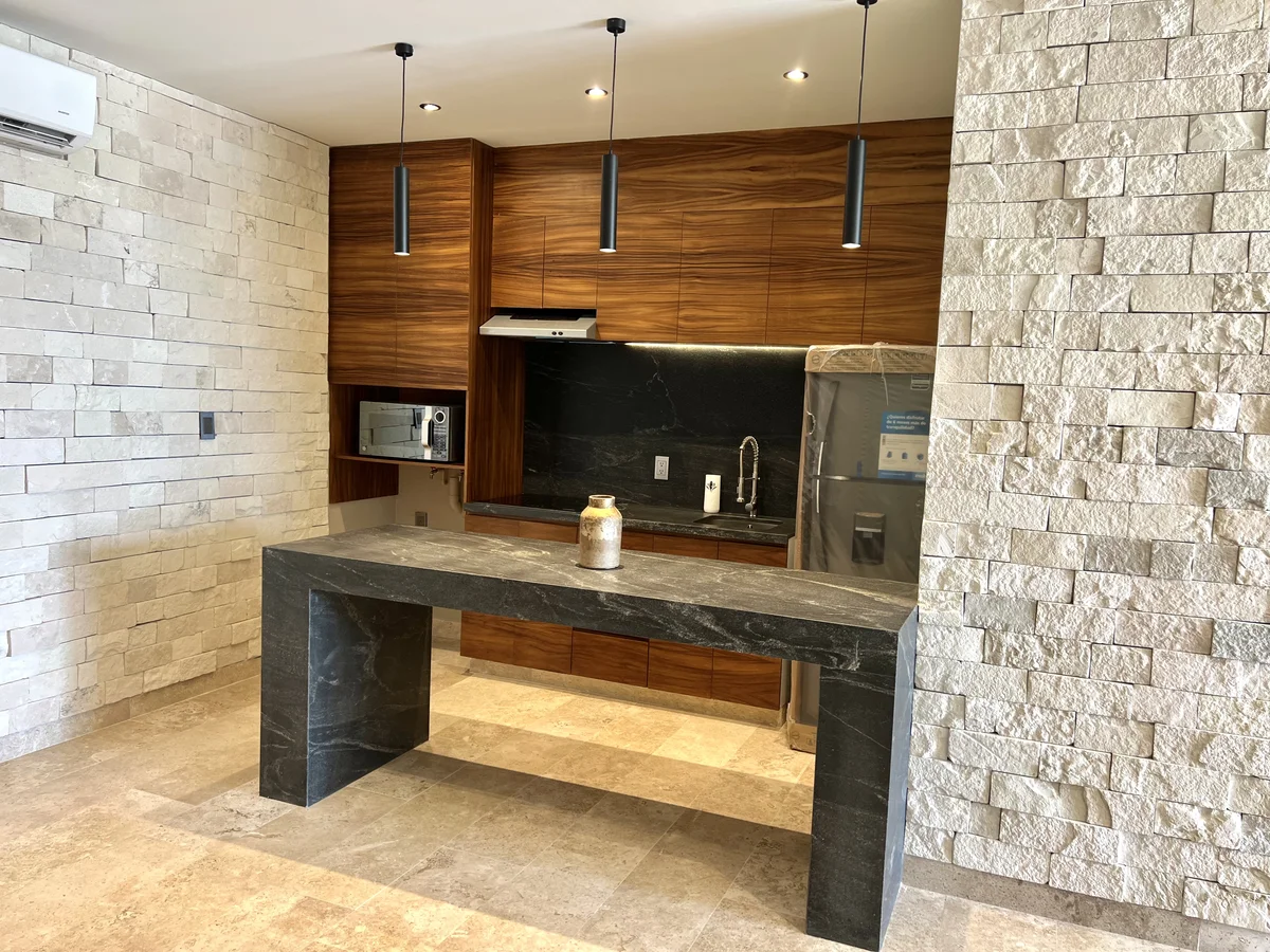 View of Modern Kitchen at Amaru, showcasing Kitchen Island, Stone Accent Wall.