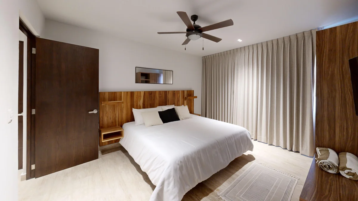 View of Modern Bedroom at Costa Caribe, showcasing Wood Headboard, Minimalist Design.