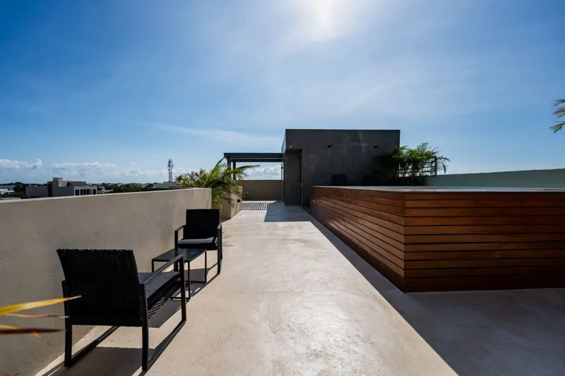 Interior view of a finished luxury unit at Amanecer Condos, featuring a minimalist design with white tiled floors, a modern kitchen area with wooden cabinetry, and an open living space, ready for occupancy.