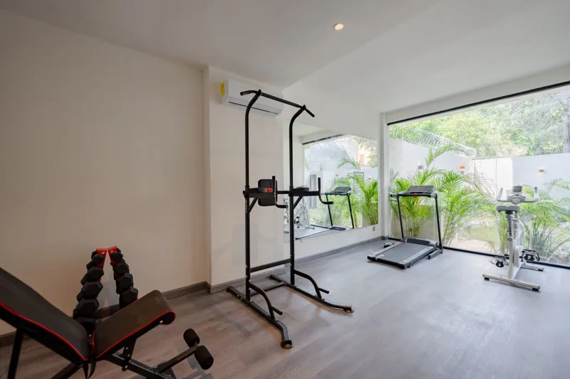 Interior view of a finished luxury unit at Amanecer Condos, featuring a minimalist design with white tiled floors, a modern kitchen area with wooden cabinetry, and an open living space, ready for occupancy.