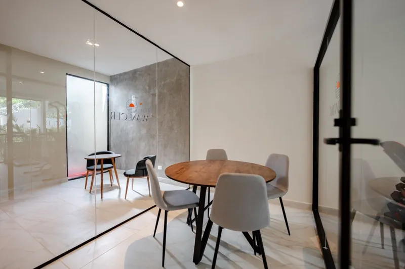 Interior view of a finished luxury unit at Amanecer Condos, featuring a minimalist design with white tiled floors, a modern kitchen area with wooden cabinetry, and an open living space, ready for occupancy.
