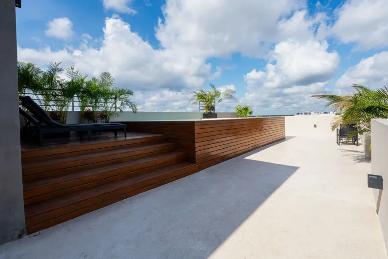 Interior view of a finished luxury unit at Amanecer Condos, featuring a minimalist design with white tiled floors, a modern kitchen area with wooden cabinetry, and an open living space, ready for occupancy.