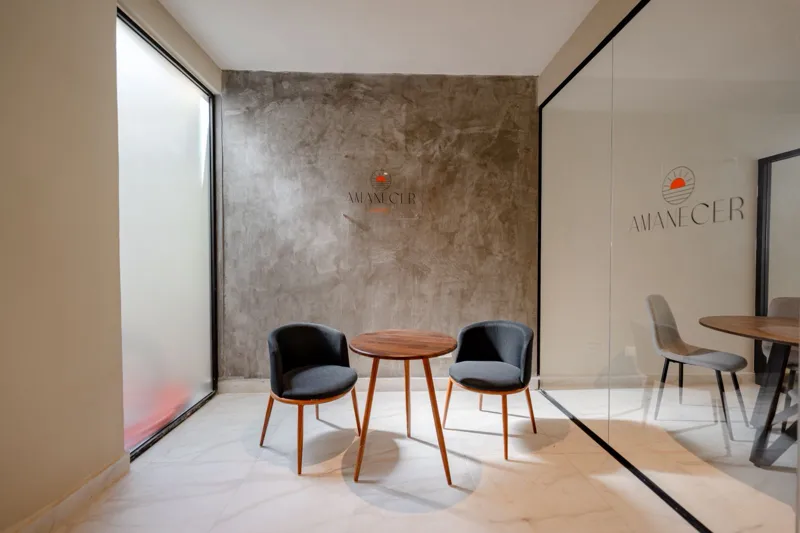 Interior view of a finished luxury unit at Amanecer Condos, featuring a minimalist design with white tiled floors, a modern kitchen area with wooden cabinetry, and an open living space, ready for occupancy.
