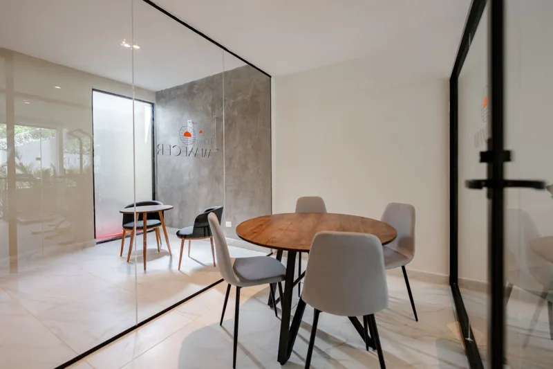 Interior view of a finished luxury unit at Amanecer Condos, featuring a minimalist design with white tiled floors, a modern kitchen area with wooden cabinetry, and an open living space, ready for occupancy.