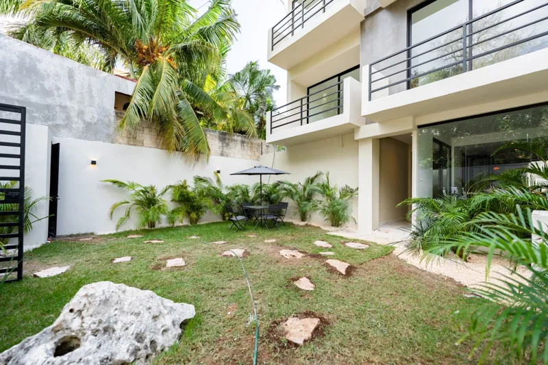 Interior view of a finished luxury unit at Amanecer Condos, featuring a minimalist design with white tiled floors, a modern kitchen area with wooden cabinetry, and an open living space, ready for occupancy.
