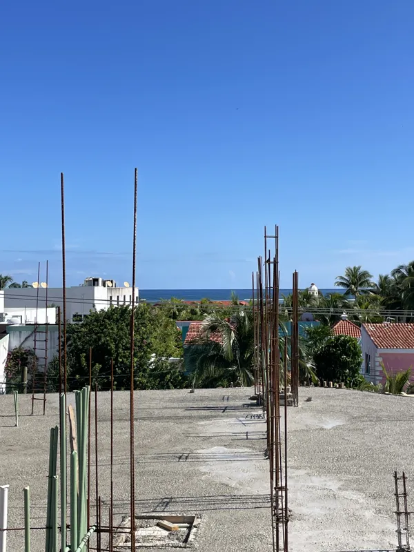 An aerial view of the Soulam development construction site shows a newly poured concrete floor slab with numerous vertical rebar structures extending upwards, indicating preparation for the next level of the building. In the background, the clear ...