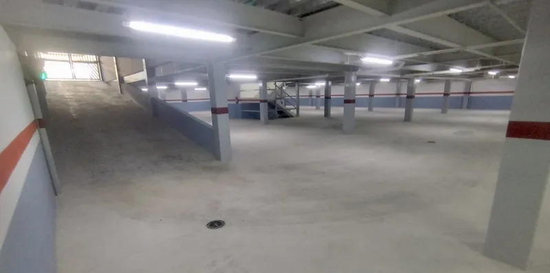 A wide shot of the sparkling rooftop infinity pool at Quartier 75, surrounded by modern lounge chairs and offering panoramic views of the city under a partly cloudy sky.