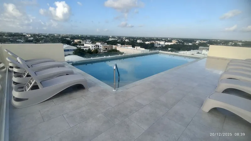 A wide shot of the sparkling rooftop infinity pool at Quartier 75, surrounded by modern lounge chairs and offering panoramic views of the city under a partly cloudy sky.