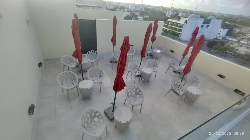 A wide shot of the sparkling rooftop infinity pool at Quartier 75, surrounded by modern lounge chairs and offering panoramic views of the city under a partly cloudy sky.