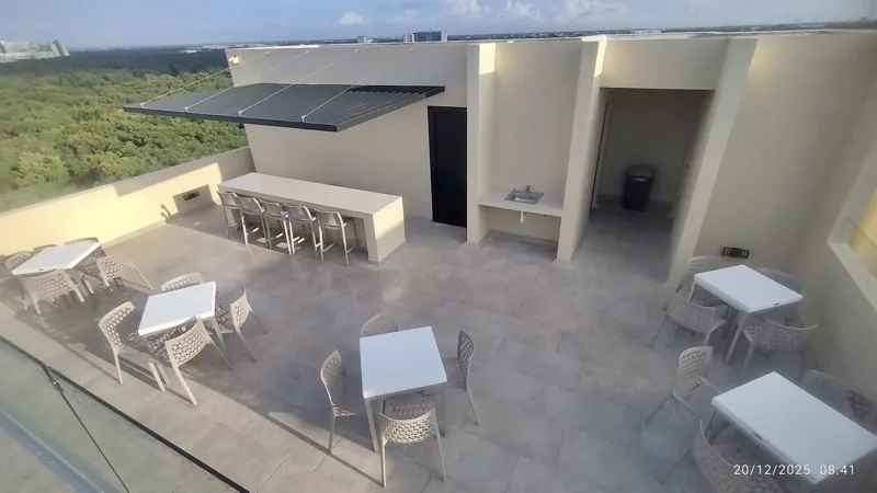 A wide shot of the sparkling rooftop infinity pool at Quartier 75, surrounded by modern lounge chairs and offering panoramic views of the city under a partly cloudy sky.