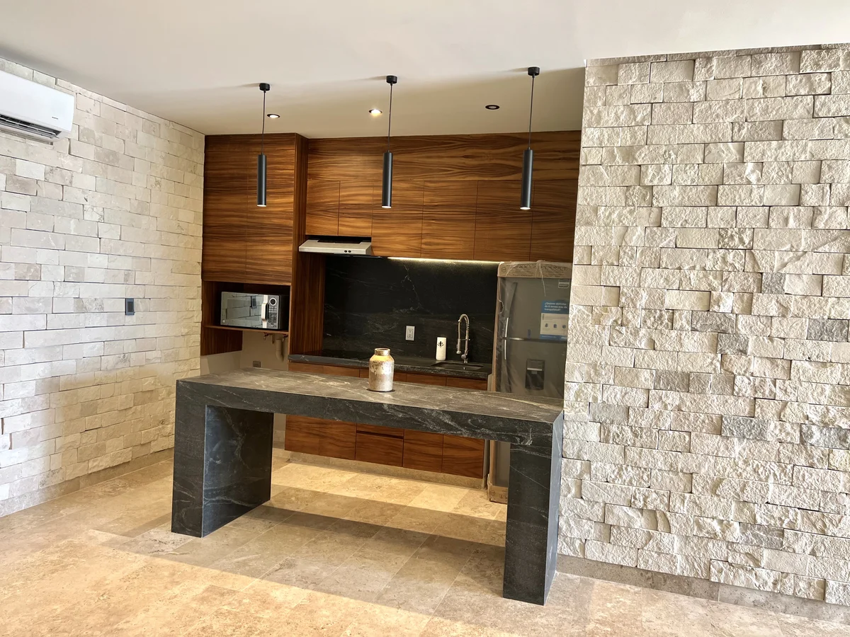 View of Modern Kitchen at Amaru, showcasing Kitchen Island, Stone Accent Wall.