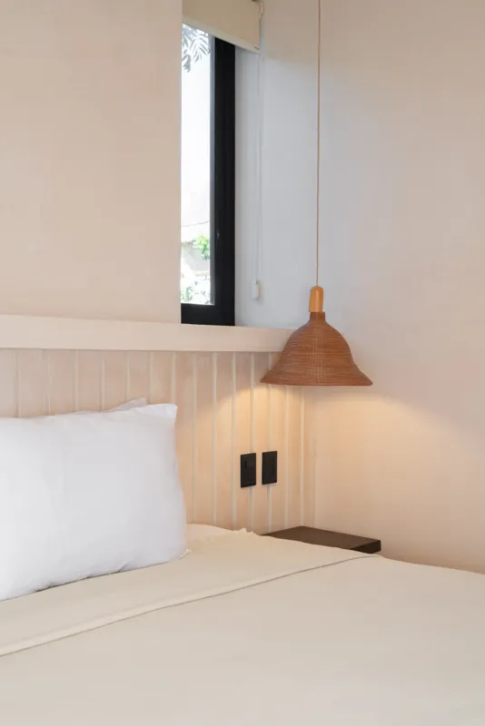 A bright, sunny rooftop terrace featuring a private swimming pool with clear blue water, surrounded by lush green plants and a light-colored building facade. A shaded pergola covers an outdoor counter area with wooden cabinets, all under a clear b...