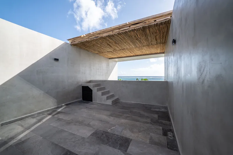 A breathtaking rooftop infinity pool at NEEA, overlooking a vibrant green jungle landscape under a bright blue sky, with a modern relaxation net area in the foreground.