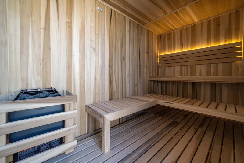 A breathtaking rooftop infinity pool at NEEA, overlooking a vibrant green jungle landscape under a bright blue sky, with a modern relaxation net area in the foreground.