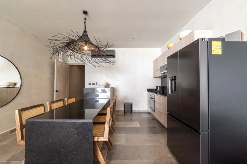 A breathtaking rooftop infinity pool at NEEA, overlooking a vibrant green jungle landscape under a bright blue sky, with a modern relaxation net area in the foreground.
