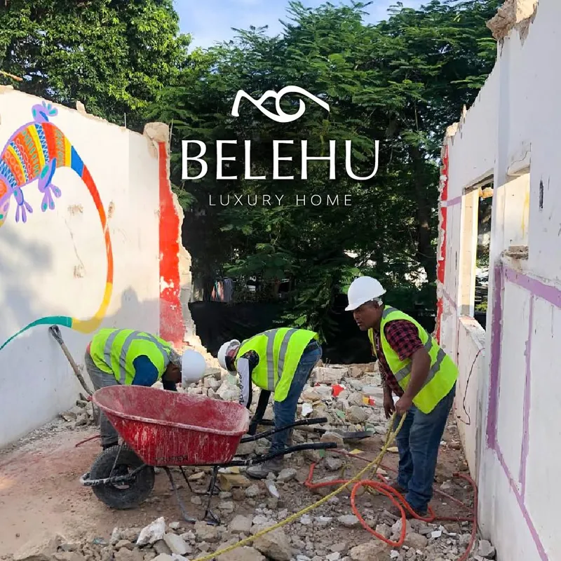 An aerial view of a demolished interior space, filled with rubble, broken concrete, and rebar, with remnants of colorful murals on the remaining walls, indicating active site preparation for the Belehu development.