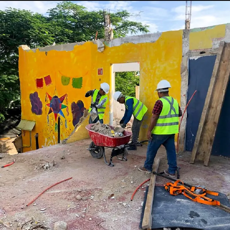 An aerial view of a demolished interior space, filled with rubble, broken concrete, and rebar, with remnants of colorful murals on the remaining walls, indicating active site preparation for the Belehu development.