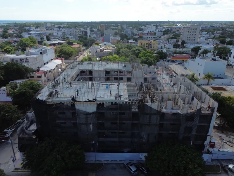 Aerial view of the Costa Celeste apartment complex under active construction in Playa del Carmen, Mexico, in January 2026. The multi-story concrete structure is well advanced, with several floors completed and rebar visible on the upper levels. Bl...
