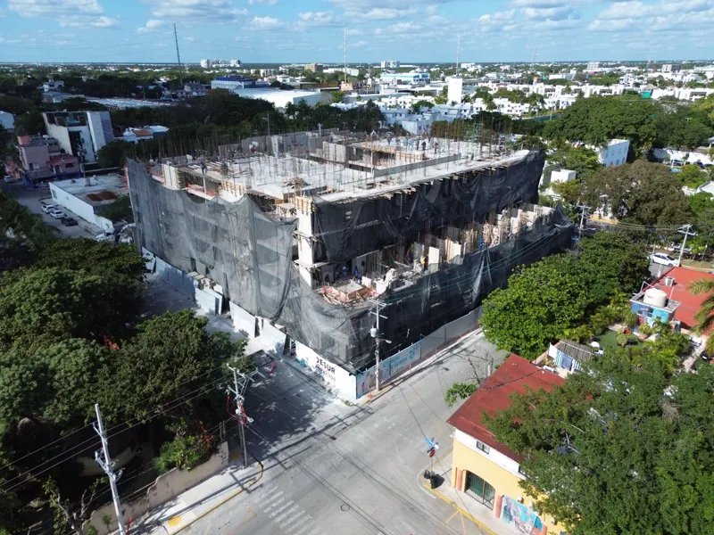 Aerial view of the Costa Celeste apartment complex under active construction in Playa del Carmen, Mexico, in January 2026. The multi-story concrete structure is well advanced, with several floors completed and rebar visible on the upper levels. Bl...
