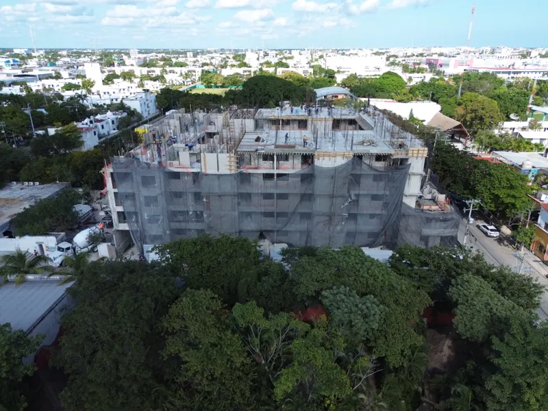 Aerial view of the Costa Celeste apartment complex under active construction in Playa del Carmen, Mexico, in January 2026. The multi-story concrete structure is well advanced, with several floors completed and rebar visible on the upper levels. Bl...
