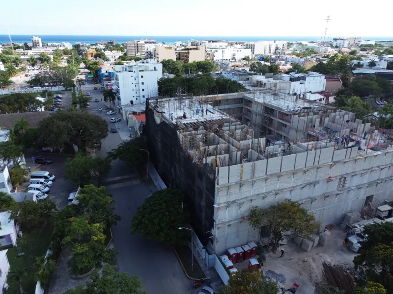 Aerial view of the Costa Celeste apartment complex under active construction in Playa del Carmen, Mexico, in January 2026. The multi-story concrete structure is well advanced, with several floors completed and rebar visible on the upper levels. Bl...