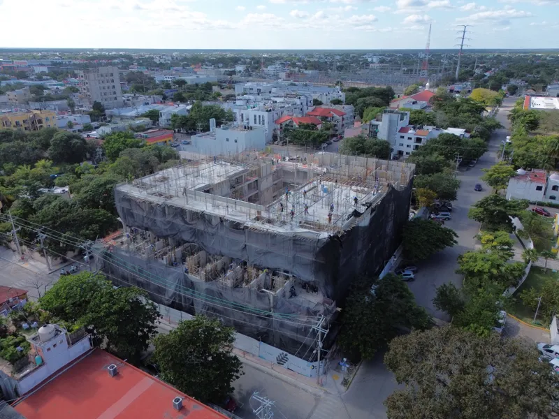 Aerial view of the Costa Celeste apartment complex under active construction in Playa del Carmen, Mexico, in January 2026. The multi-story concrete structure is well advanced, with several floors completed and rebar visible on the upper levels. Bl...
