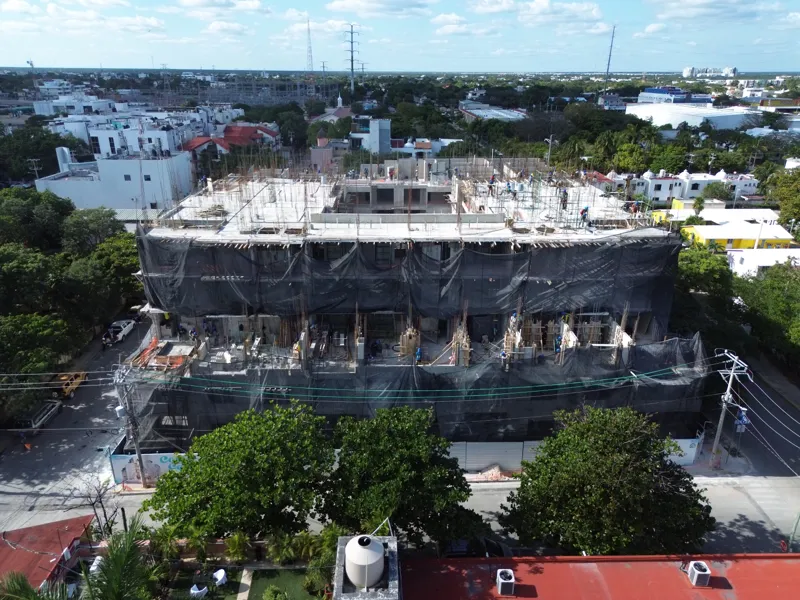 Aerial view of the Costa Celeste apartment complex under active construction in Playa del Carmen, Mexico, in January 2026. The multi-story concrete structure is well advanced, with several floors completed and rebar visible on the upper levels. Bl...