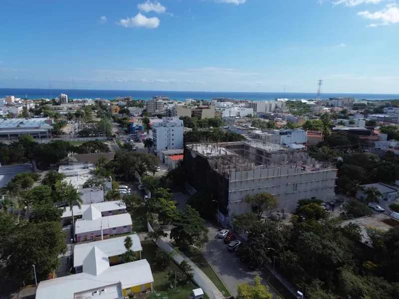 Aerial view of the Costa Celeste apartment complex under active construction in Playa del Carmen, Mexico, in January 2026. The multi-story concrete structure is well advanced, with several floors completed and rebar visible on the upper levels. Bl...