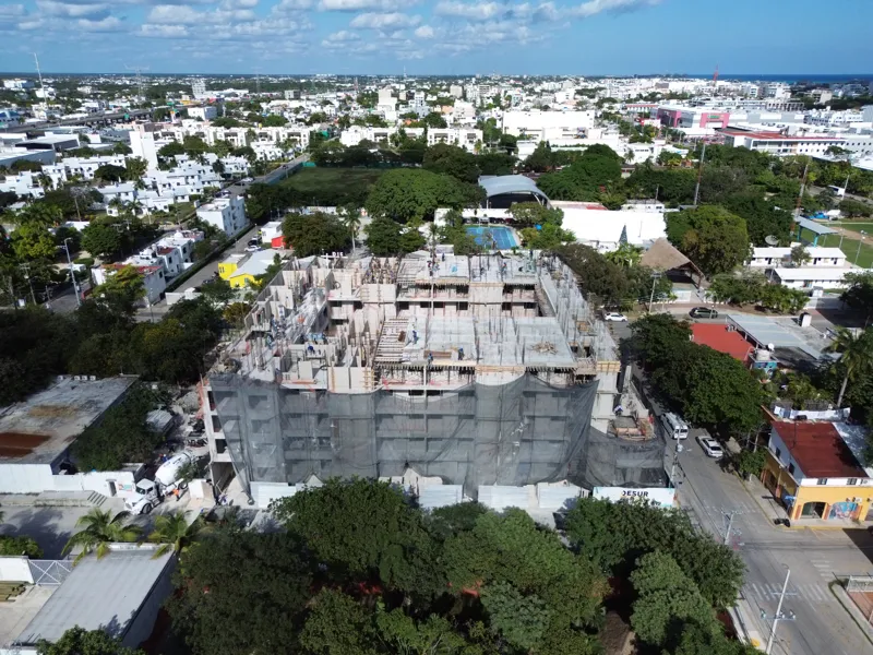 Aerial view of the Costa Celeste apartment complex under active construction in Playa del Carmen, Mexico, in January 2026. The multi-story concrete structure is well advanced, with several floors completed and rebar visible on the upper levels. Bl...