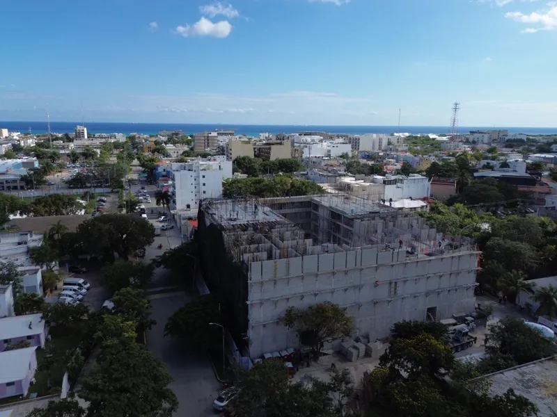 Aerial view of the Costa Celeste apartment complex under active construction in Playa del Carmen, Mexico, in January 2026. The multi-story concrete structure is well advanced, with several floors completed and rebar visible on the upper levels. Bl...