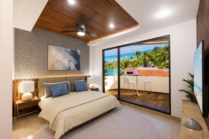 A beautifully rendered modern living room featuring a light-colored sofa, a wooden coffee table, and a ceiling fan, with a large sliding glass door opening to a balcony that offers a panoramic view of the turquoise Caribbean Sea and lush palm trees.