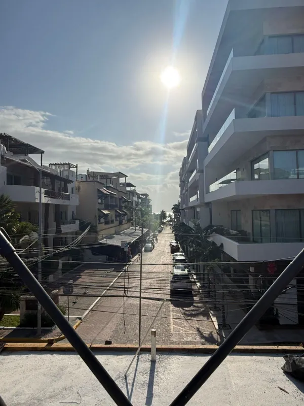 An active construction site for Costera Mamitas under a bright blue sky, featuring multiple workers in safety gear, rebar extending upwards, and wooden concrete forms, indicating significant structural progress.