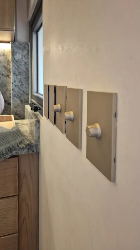 A beautifully furnished dining area with a wooden table set for four, surrounded by modern wooden chairs, leading into a contemporary kitchen with dark wood cabinets, light granite countertops, and stainless steel appliances, all under warm accent...