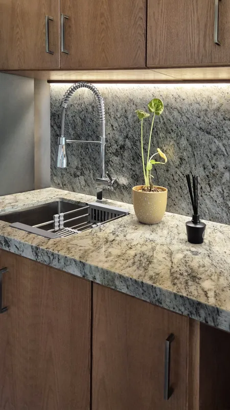 A beautifully furnished dining area with a wooden table set for four, surrounded by modern wooden chairs, leading into a contemporary kitchen with dark wood cabinets, light granite countertops, and stainless steel appliances, all under warm accent...