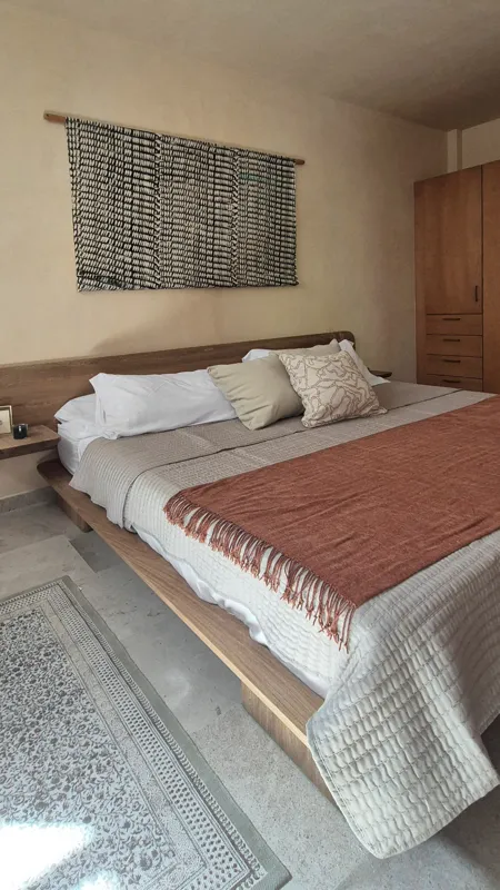 A beautifully furnished dining area with a wooden table set for four, surrounded by modern wooden chairs, leading into a contemporary kitchen with dark wood cabinets, light granite countertops, and stainless steel appliances, all under warm accent...